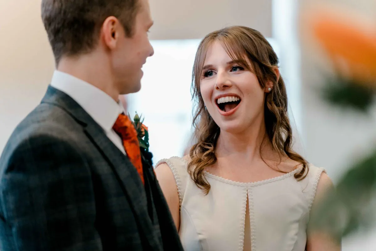 A joyful bride laughing happily while looking at her groom during their wedding ceremony.
