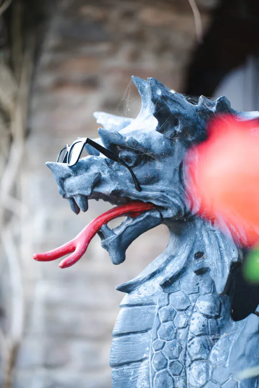 A stone dragon statue wearing sunglasses and displaying a bright red tongue stands as a quirky decorative detail at a castle wedding.