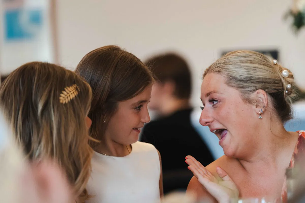 A guest and young wedding attendees share a joyful, animated conversation during the wedding reception.