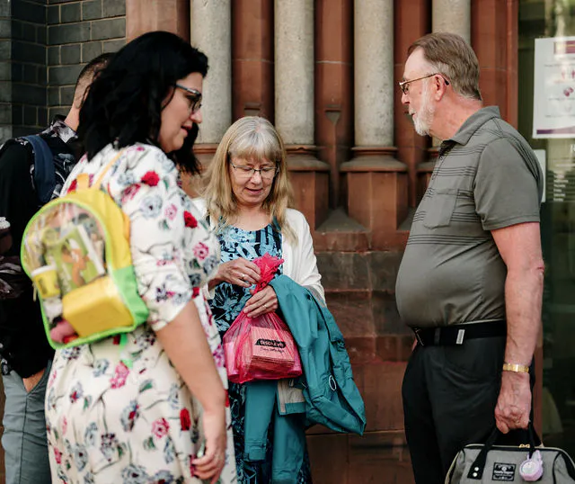 Wedding guests converse and mingle casually outside a building with architectural column details.