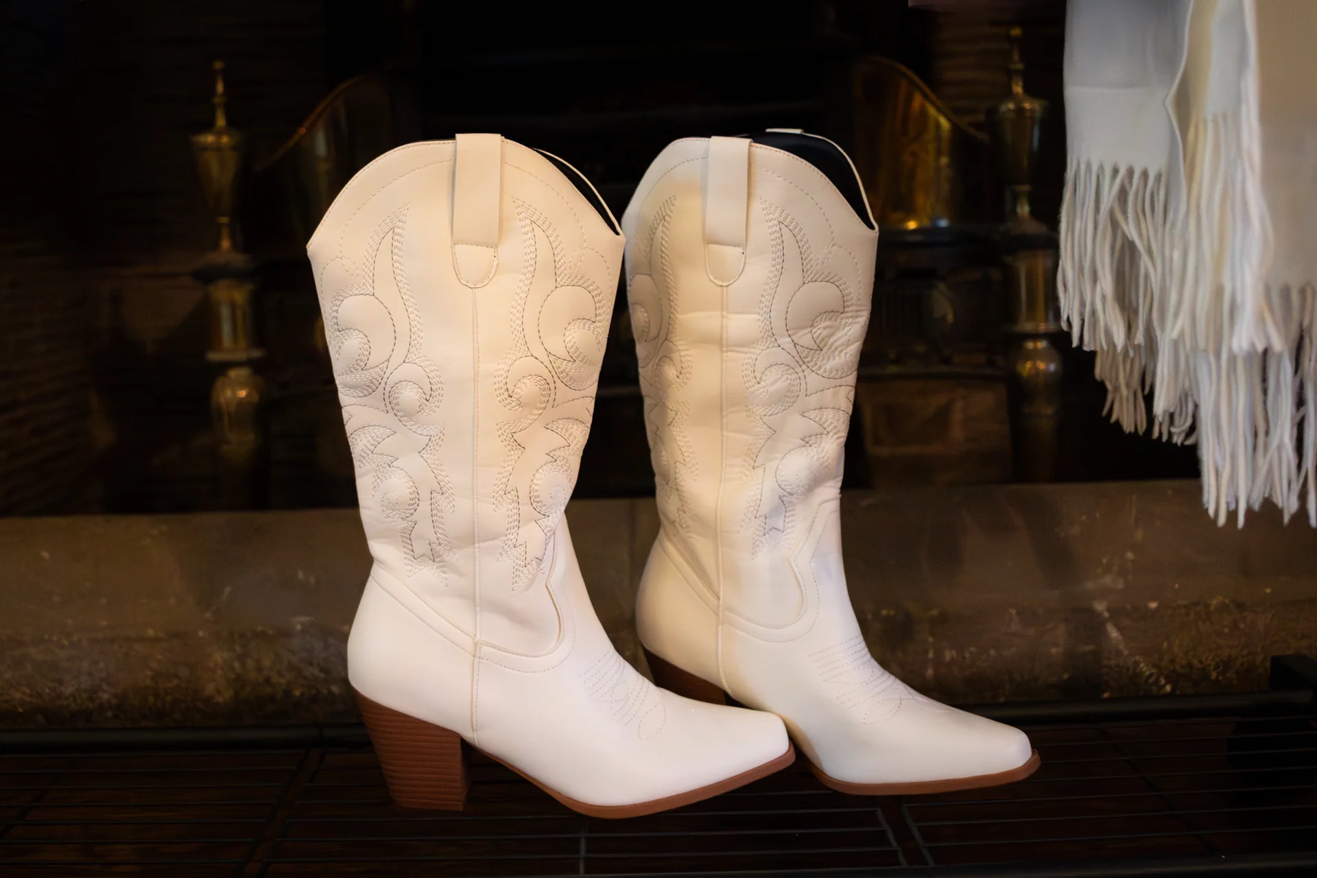 A pair of white leather cowboy boots with stitched detailing sit side-by-side as part of bridal preparations.