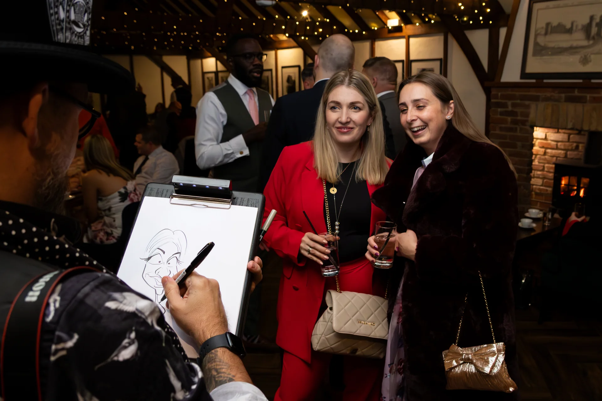 A wedding guest laughs heartily as a live caricaturist sketches her portrait on a clipboard during the evening reception.