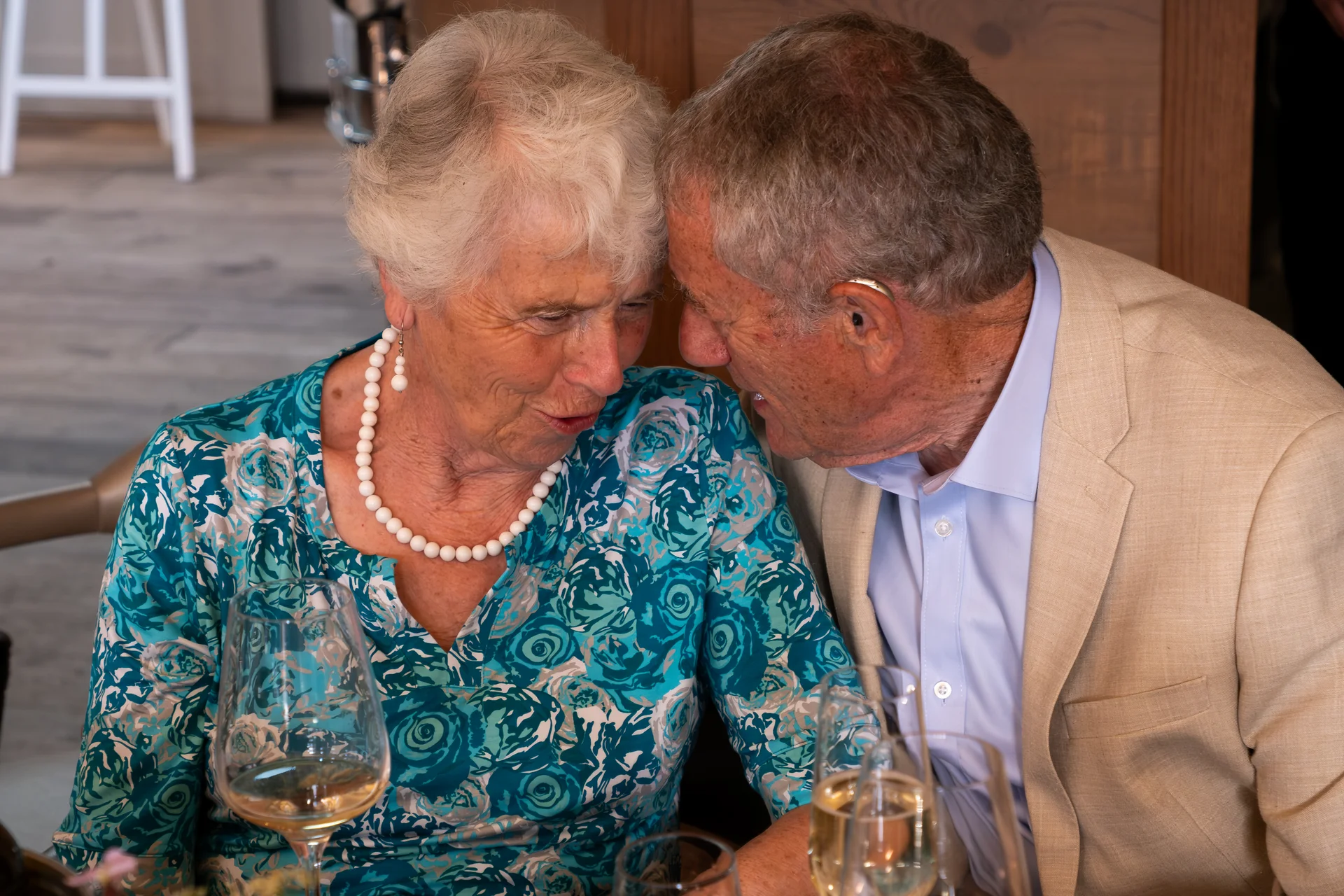 An older couple shares a tender, intimate moment with their heads gently touching during a wedding reception.
