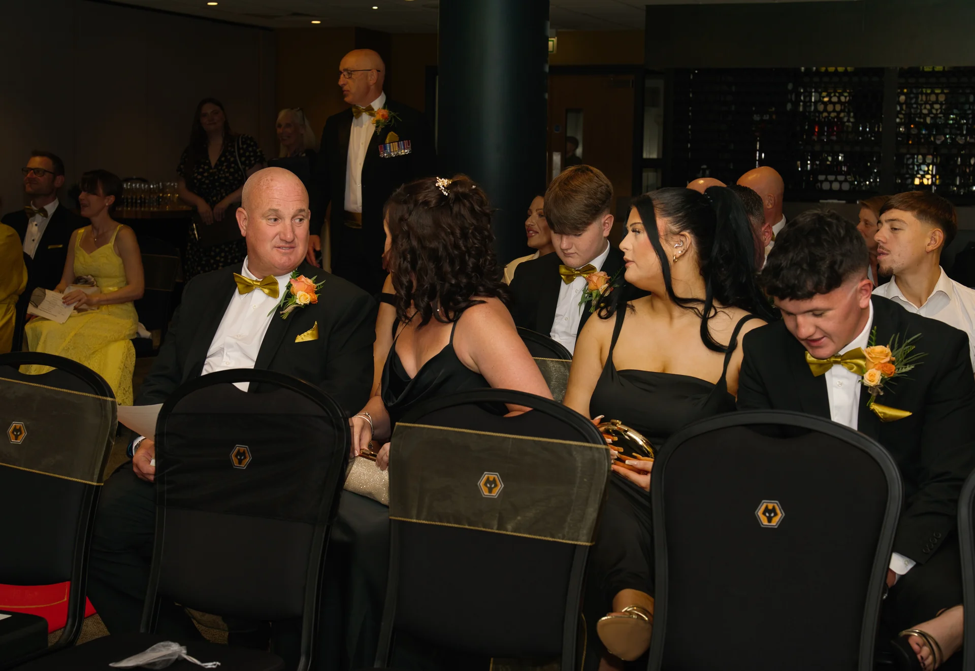 A candid shot of wedding guests dressed in formal attire seated in rows for the ceremony.