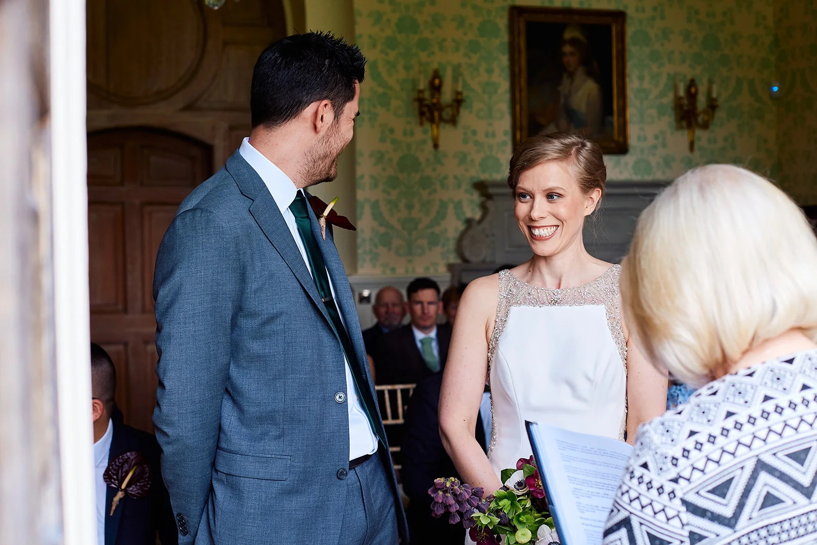 A smiling bride and groom share a loving glance during their civil ceremony inside an elegant panelled room.