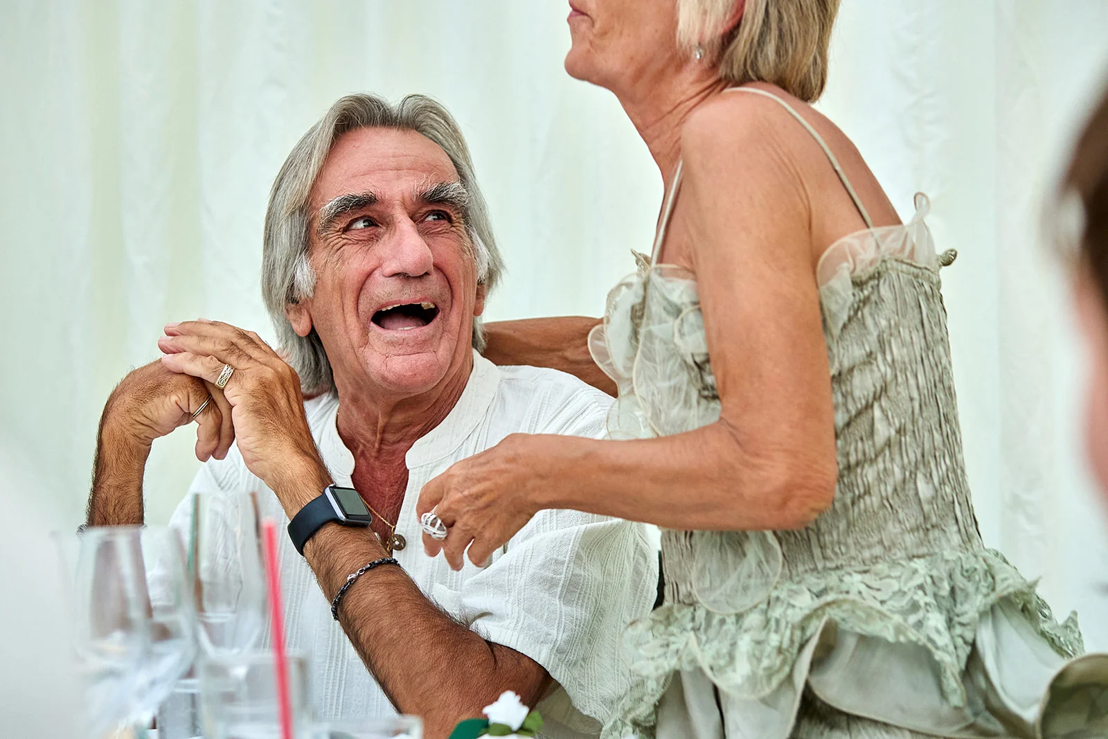 An older couple shares a joyful moment of laughter together during the wedding reception speeches.