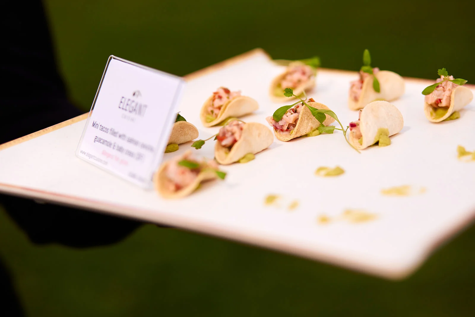 A white platter filled with gourmet mini tacos served as canapes during a wedding reception.
