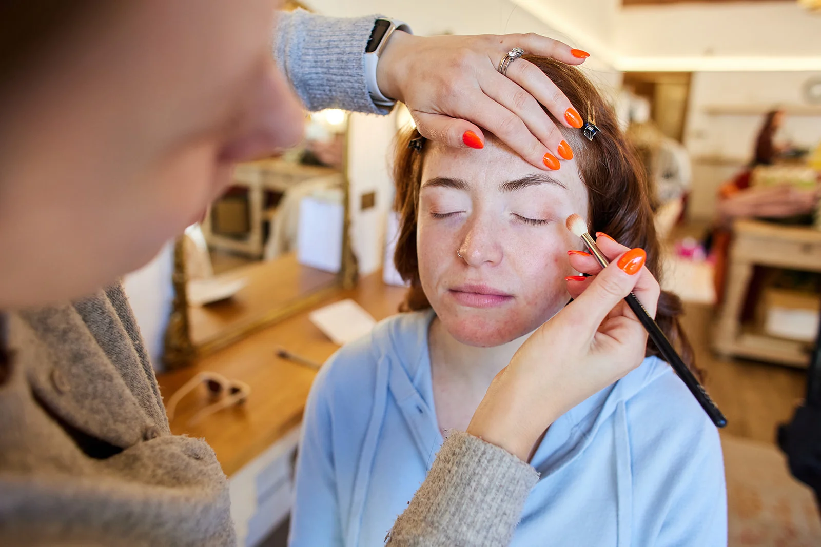 A makeup artist delicately applies eyeshadow to a bride during morning bridal preparations.
