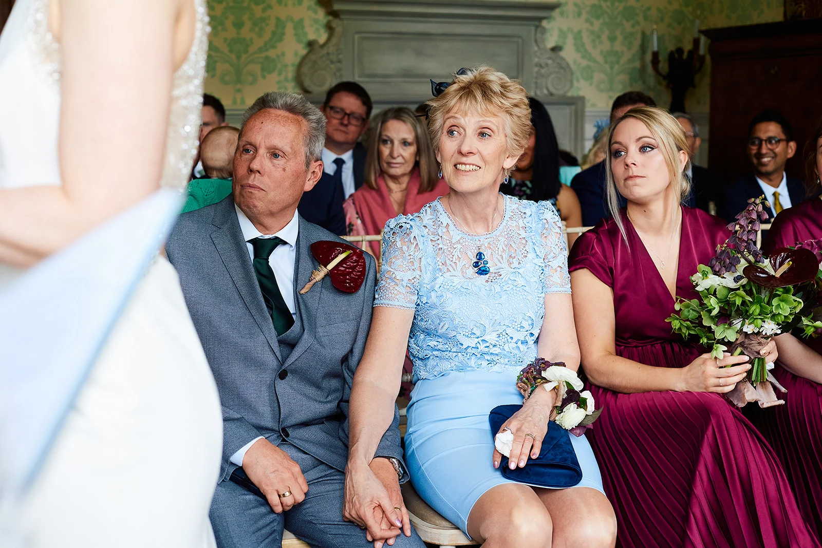 Emotional parents and wedding guests watch the ceremony from the front row as the bride stands before them.