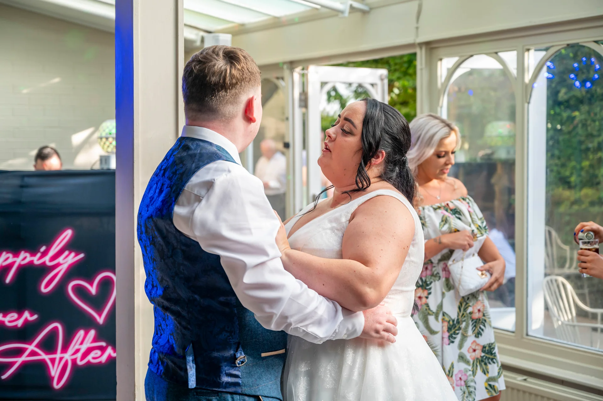 The bride and groom share a tender moment during their first dance inside a bright conservatory wedding venue.
