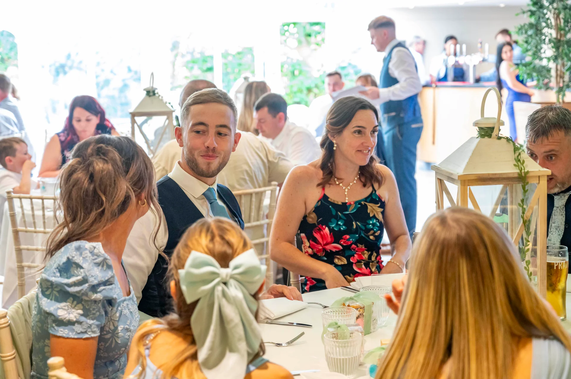 Wedding guests enjoy conversation and drinks during a bright daytime wedding breakfast.
