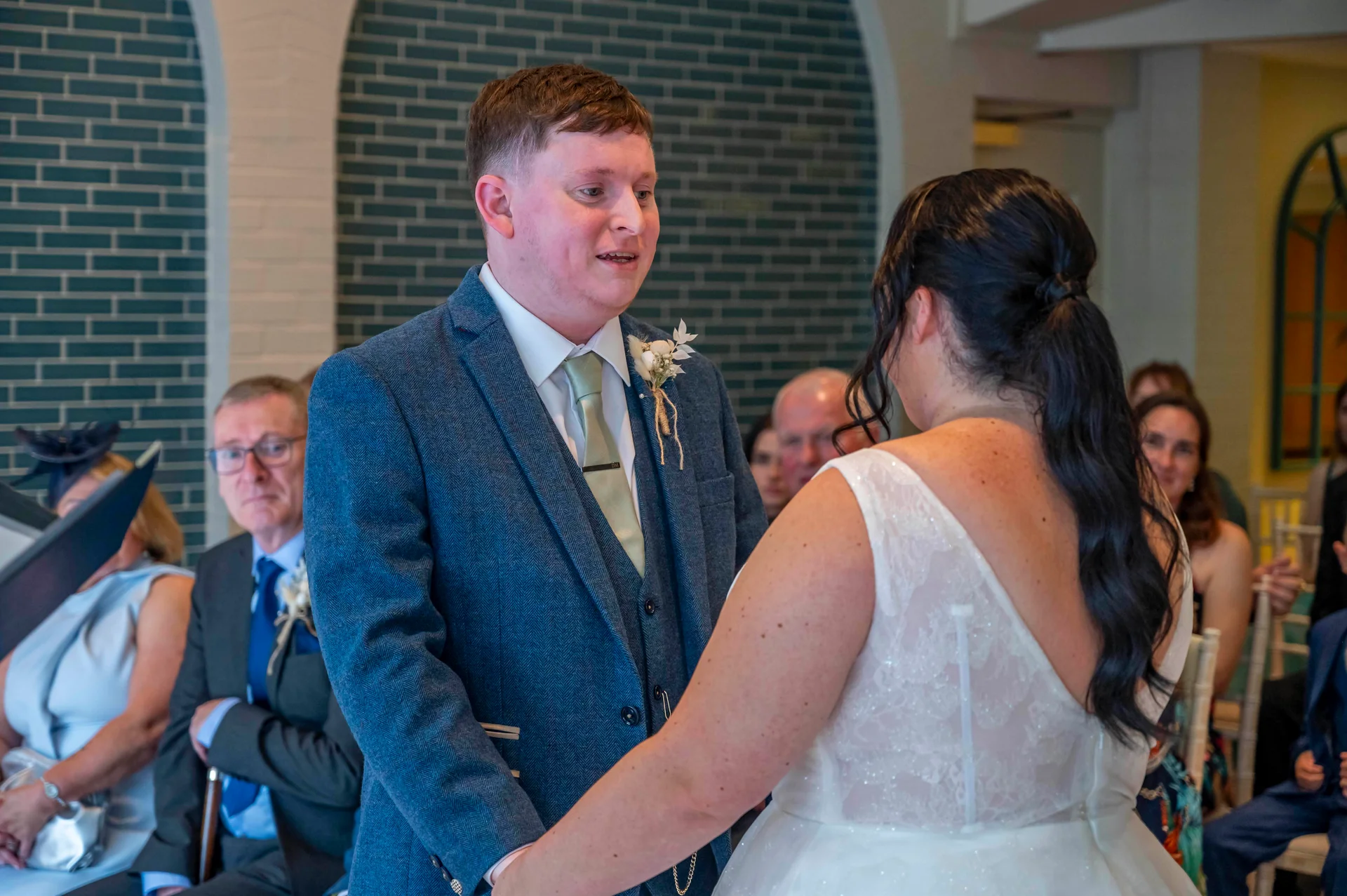 The groom looks emotionally at his bride during their civil ceremony while holding hands at the altar.