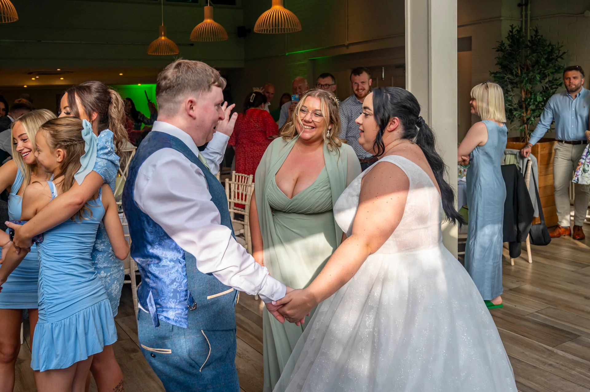 The newlyweds share a joyful dance together while surrounded by smiling guests during their wedding reception.