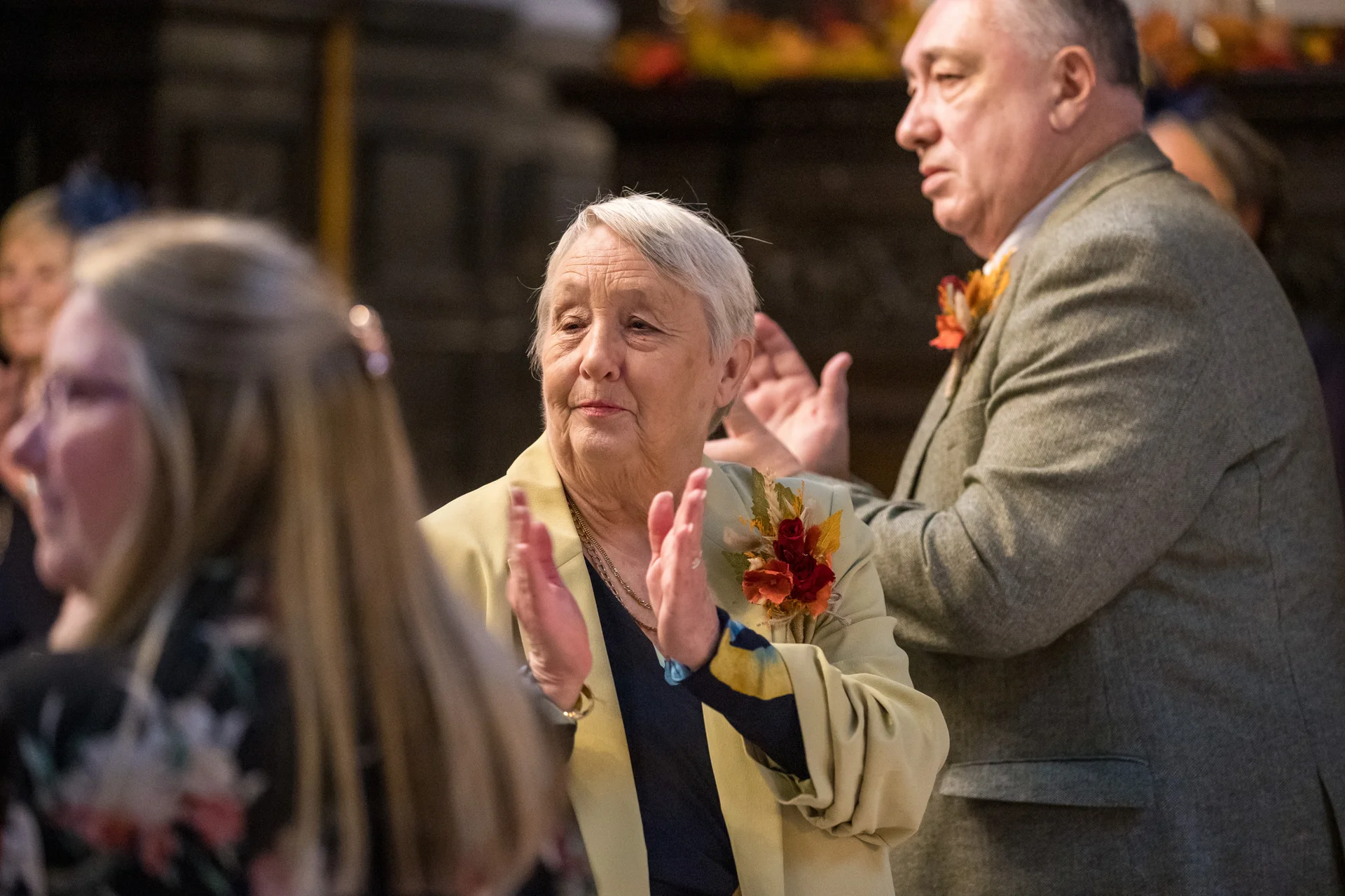 Elderly wedding guests stand and applaud warmly with joyful expressions during the ceremony or reception.