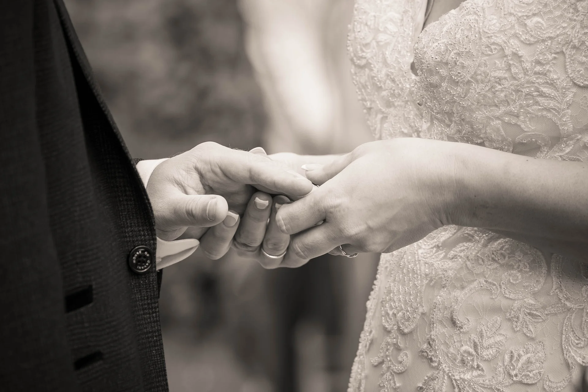 A close-up shot capturing the bride and groom exchanging wedding rings, with the bride gently placing a band on the groom's finger.
