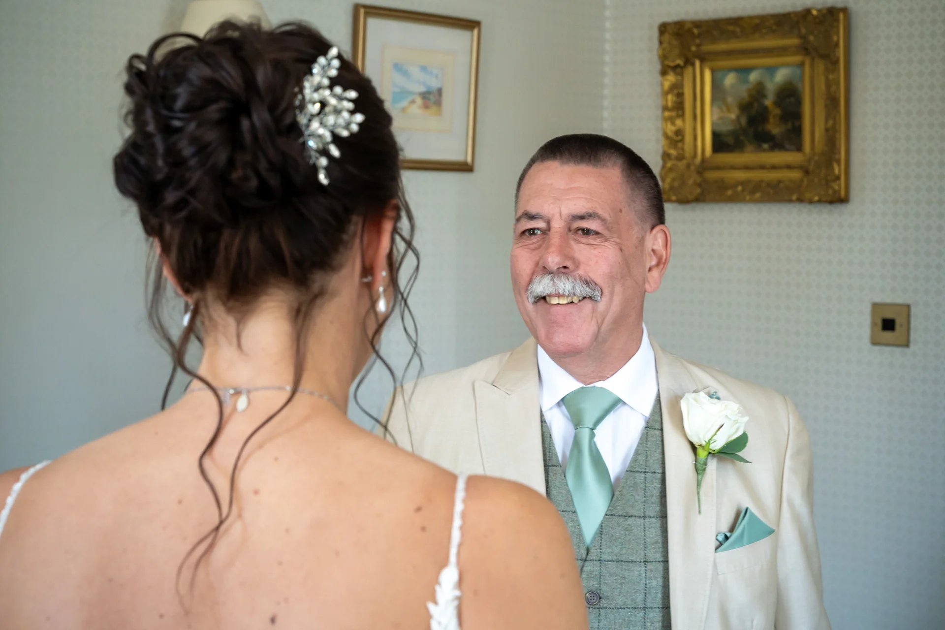 A proud father smiles warmly as he shares a special first look moment with his daughter on her wedding day.