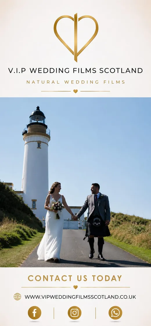 A newlywed couple walks hand in hand along a coastal path, smiling at each other with a striking white lighthouse in the background under a clear blue sky.