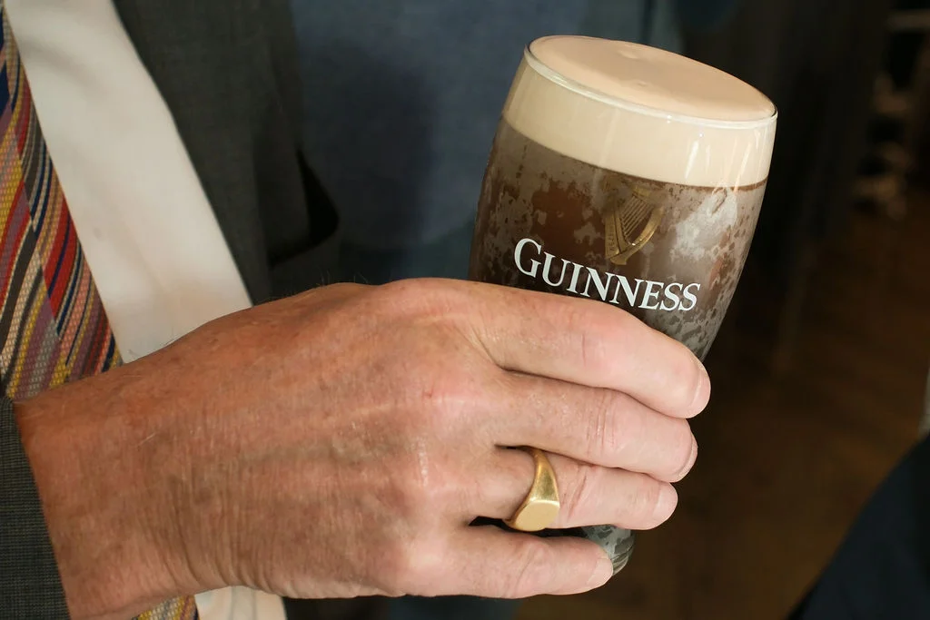 A wedding guest holding a pint of Guinness during a drinks reception at a pub wedding.