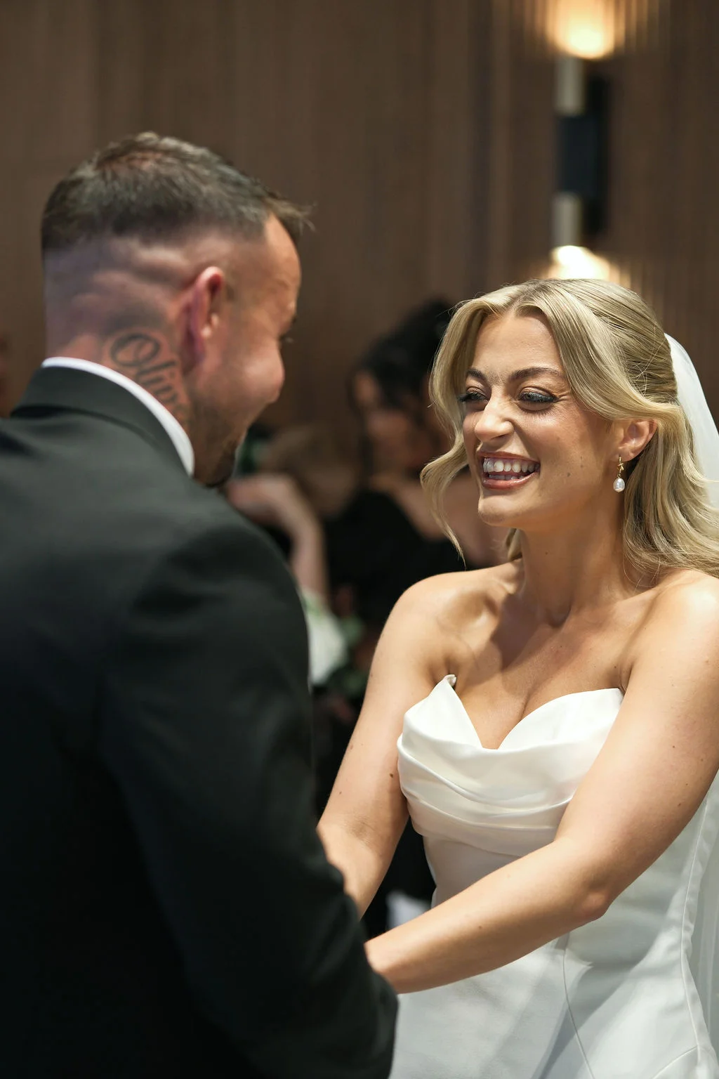 A joyful bride laughs happily while sharing a tender moment with her groom during the wedding ceremony.