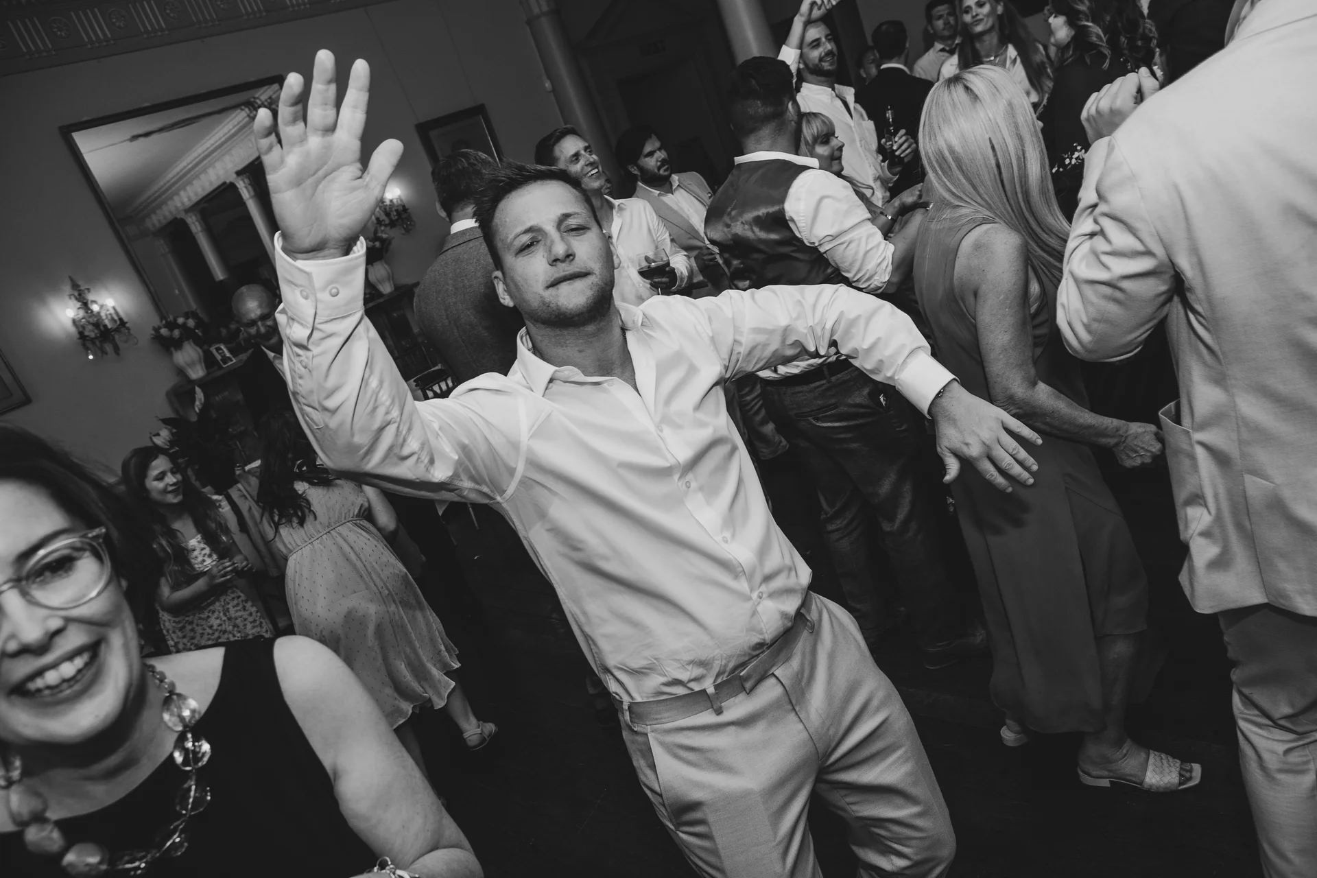A guest dances enthusiastically with his arm raised high on a lively evening dance floor.