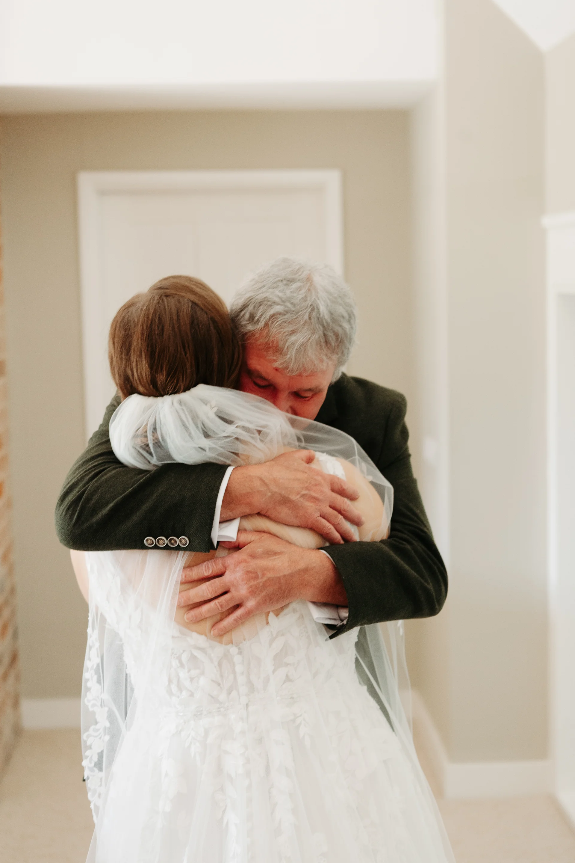 A father and bride share a tender, emotional embrace during a first look moment before the ceremony.