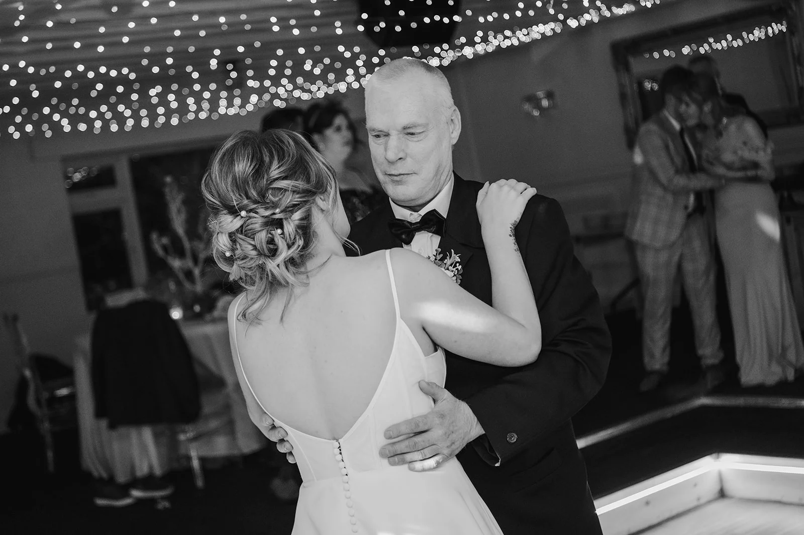 A bride and her father share a tender father-daughter dance under a canopy of fairy lights during the evening reception.