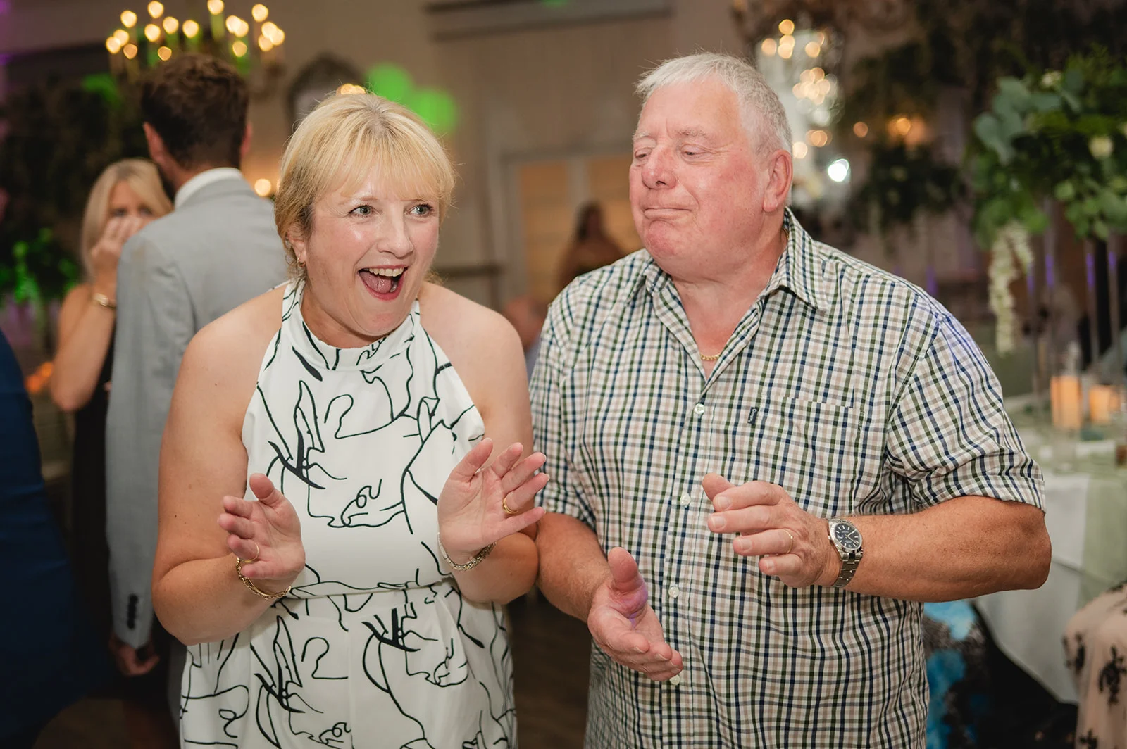 Two wedding guests laugh and clap enthusiastically during the evening reception celebrations.