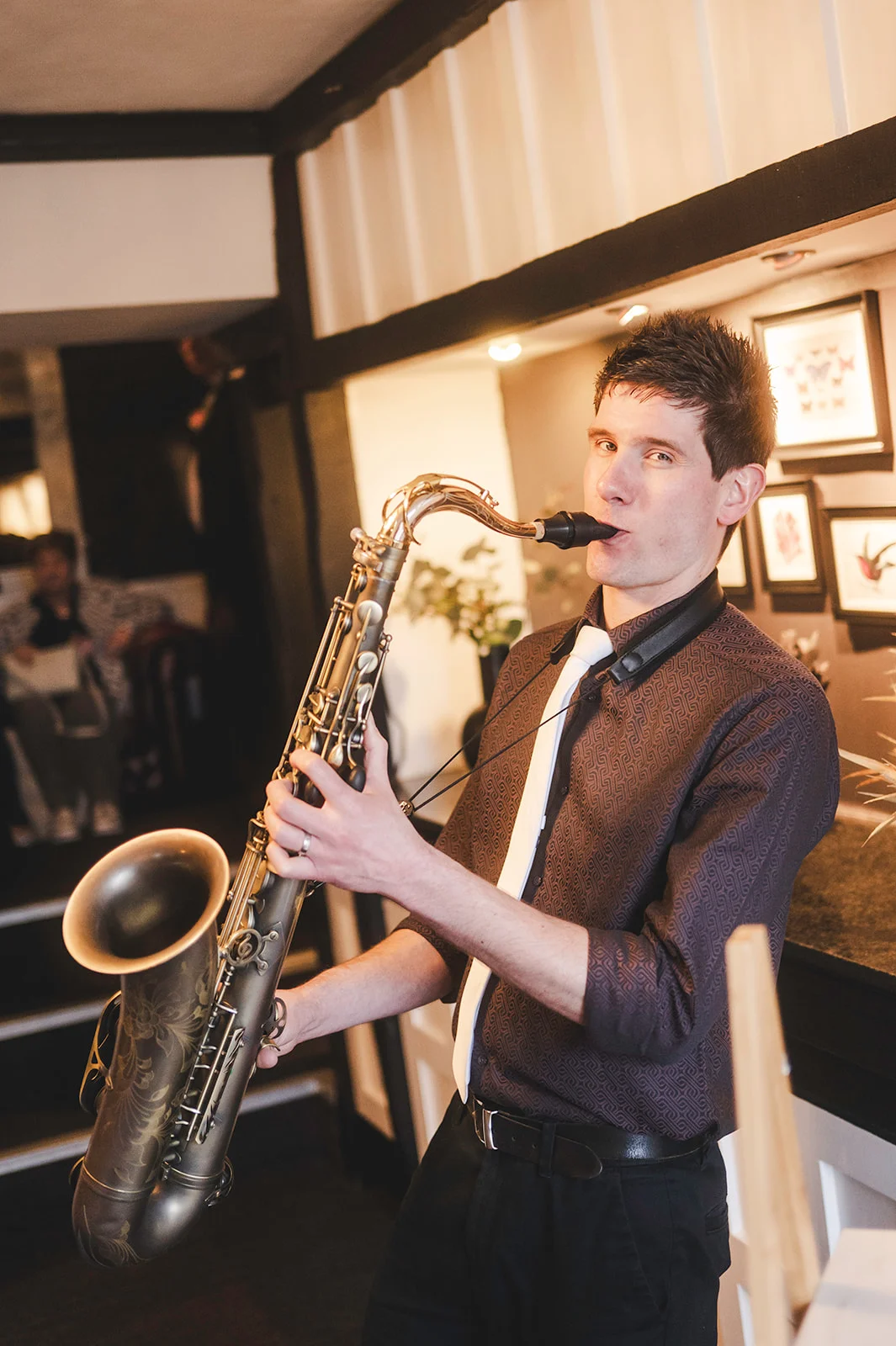A talented saxophonist plays his instrument during a wedding reception inside a charming pub venue.