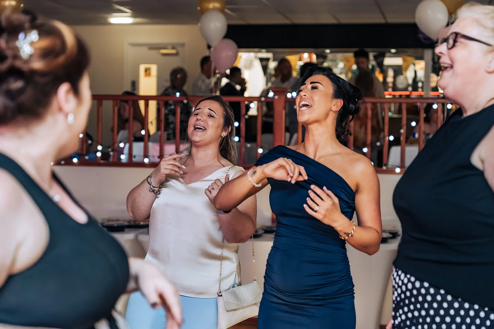 Group of wedding guests laughing and dancing together enthusiastically during the evening reception.