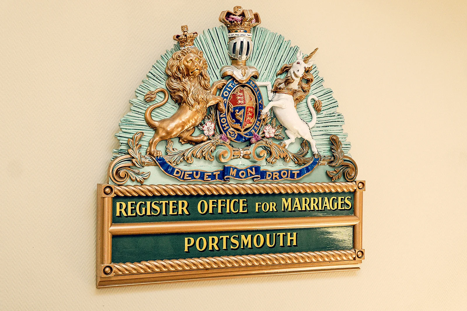 A detailed close-up shot of the ornate royal coat of arms plaque above the Portsmouth Register Office sign.