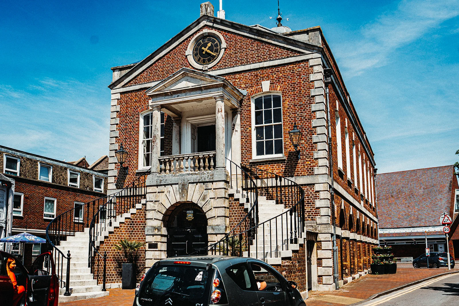 A magnificent historic red brick town hall with twin sweeping stone staircases under a brilliant blue sky on a sunny wedding day.