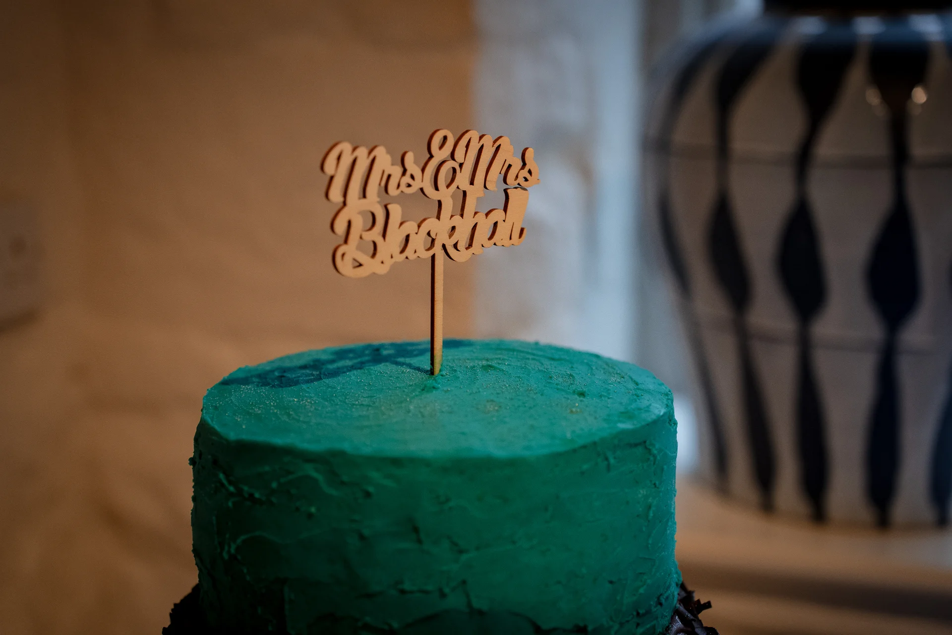 A vibrant single-tier teal wedding cake featuring a rustic textured buttercream finish and a personalised wooden topper.