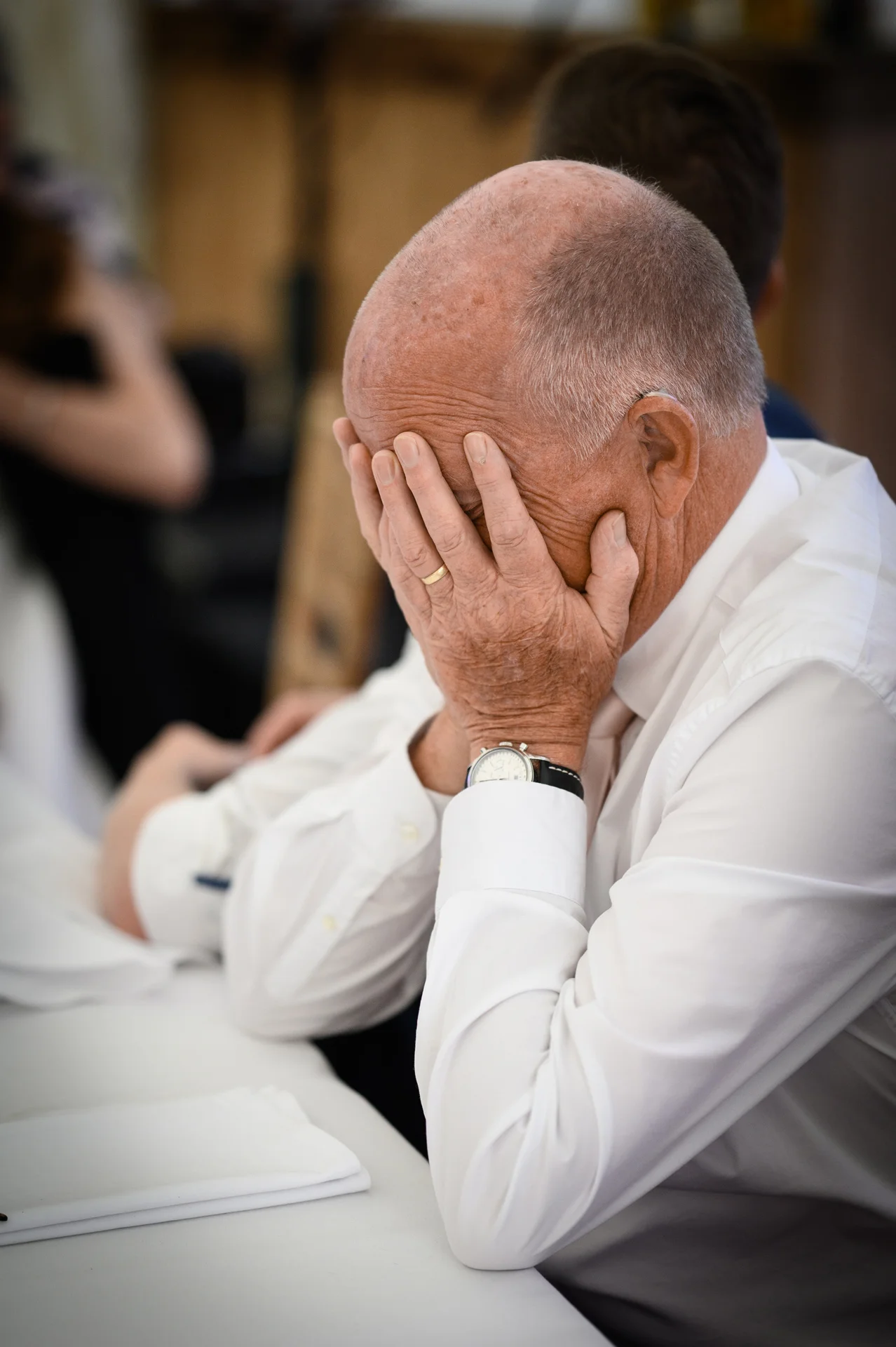 A guest at a wedding reception covers his face with his hands in an emotional moment during the speeches.