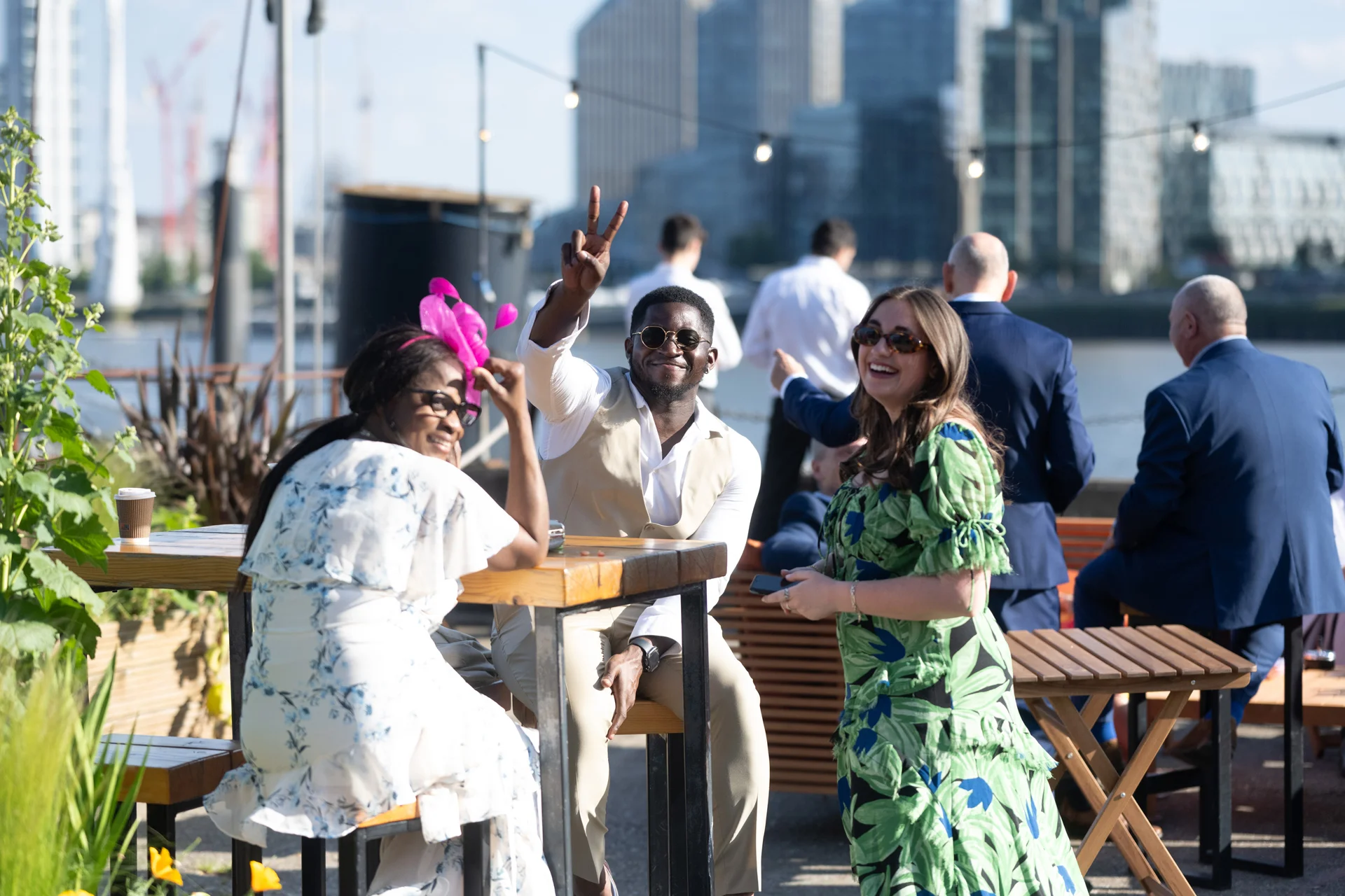 Wedding guests enjoy a drinks reception on a sunny rooftop terrace overlooking the city skyline.