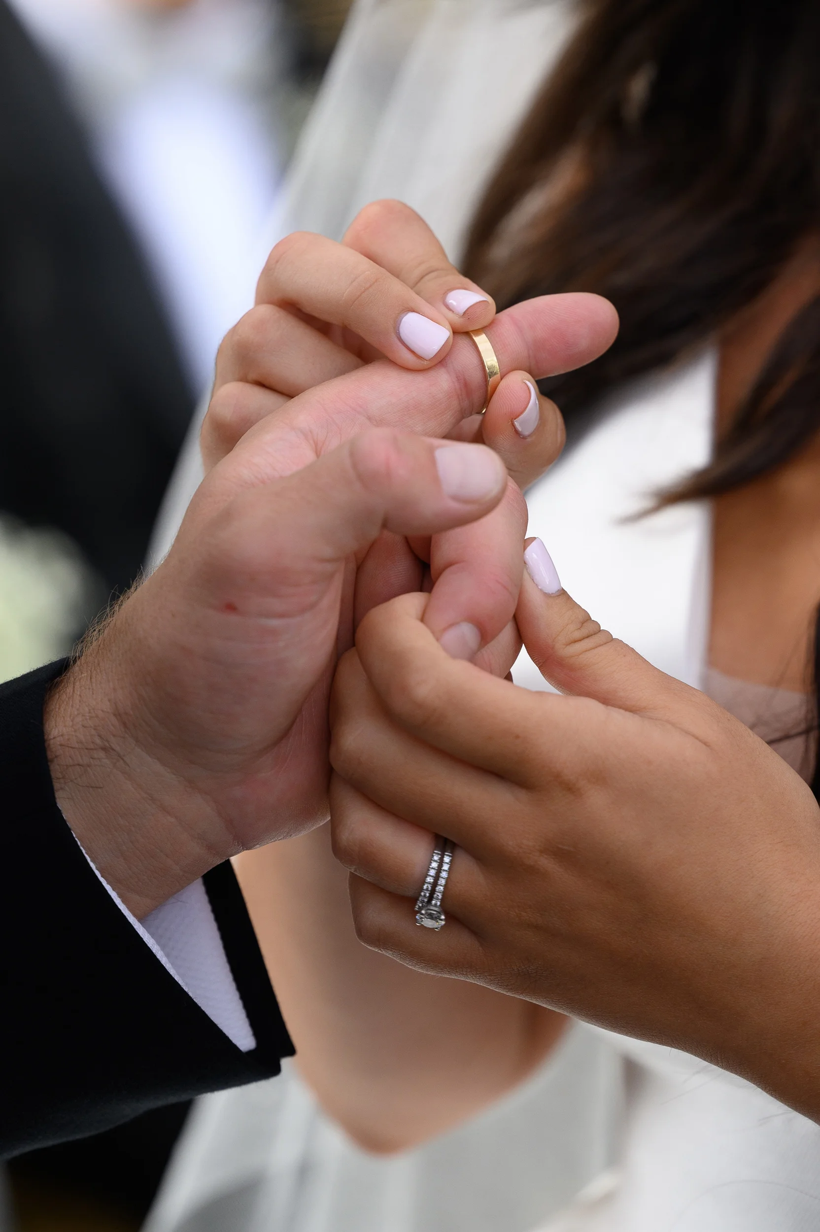Close-up shot capturing the traditional moment during the wedding ceremony as the couple exchanges wedding bands on each other's fingers.