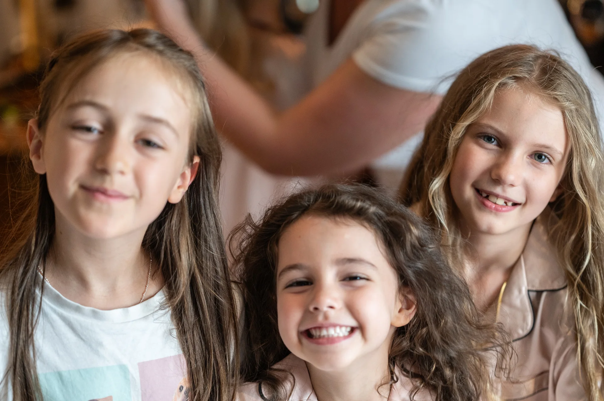 Three young girls smiling and laughing together indoors during wedding morning preparations.
