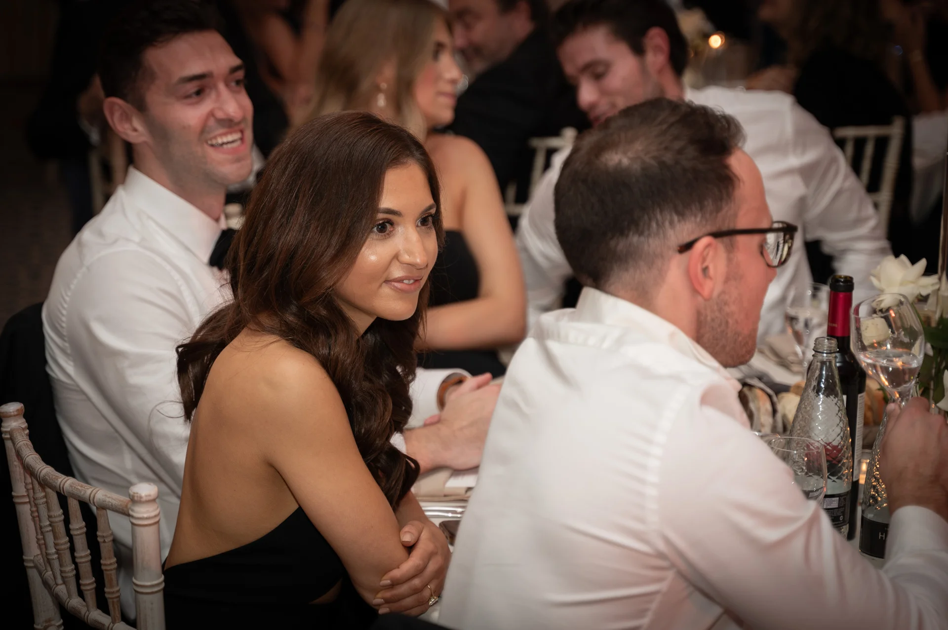 Wedding guests smiling and chatting animatedly around a elegantly set dinner table during the wedding reception.