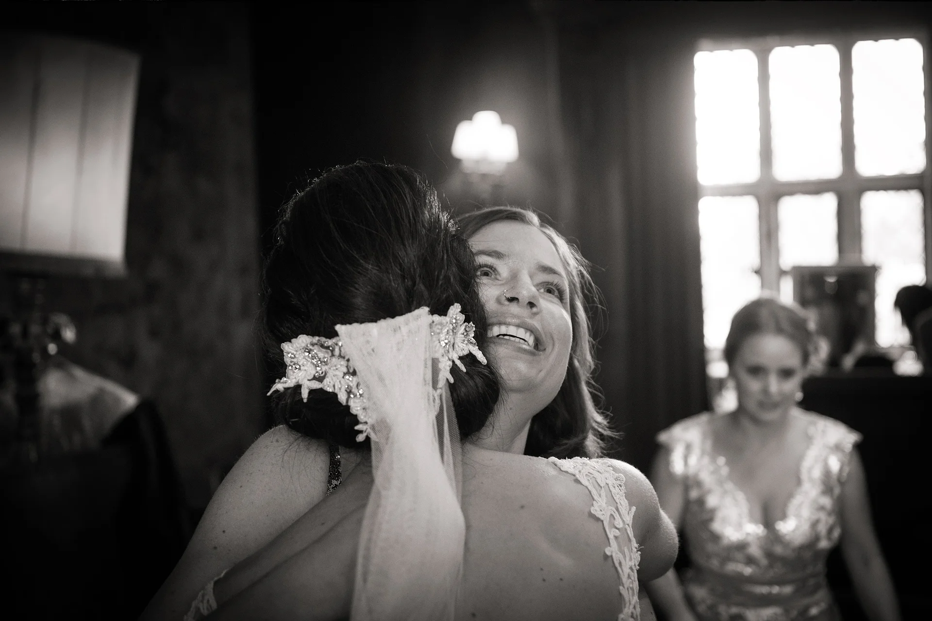 A joyous bride laughing while embracing her partner in a tender moment captured in black and white.