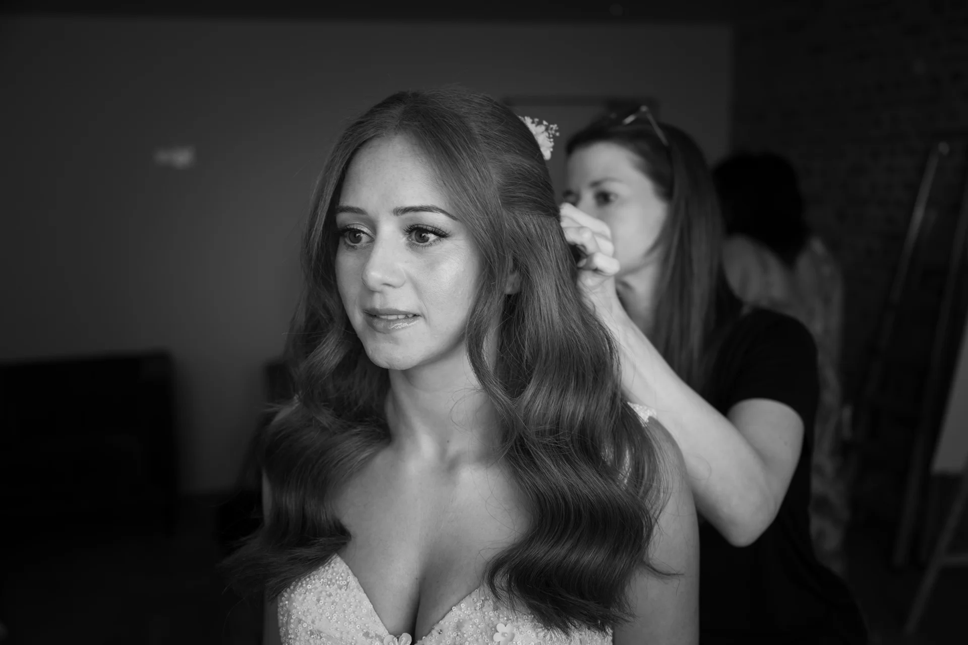 A stunning black and white portrait of a bride having her long hair styled in soft waves during morning preparations.